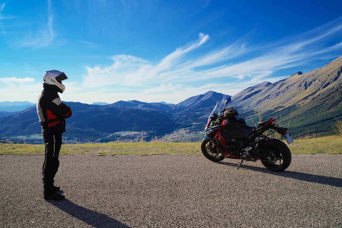 Man Standing next to motorcycle on top of a hill